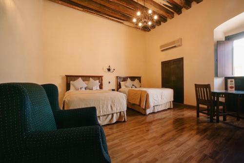 a room with two beds and a table and chairs at Hotel Casa Antigua in Oaxaca City