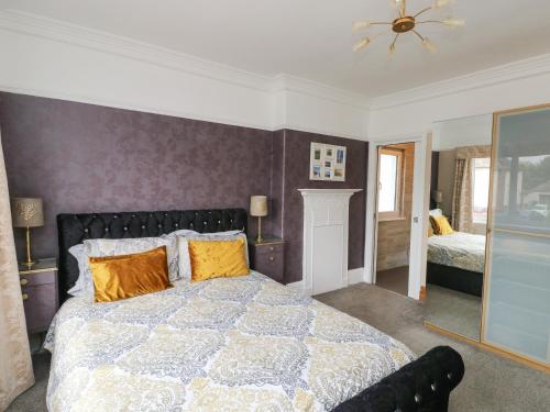 um quarto com uma cama grande e almofadas amarelas em Glendalough em Colwyn Bay