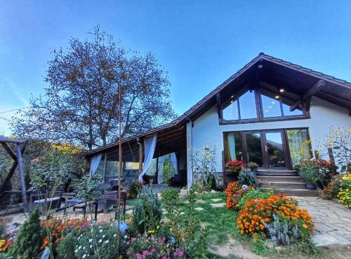 a house with a bunch of flowers in the yard at Casa Her in Galaţi