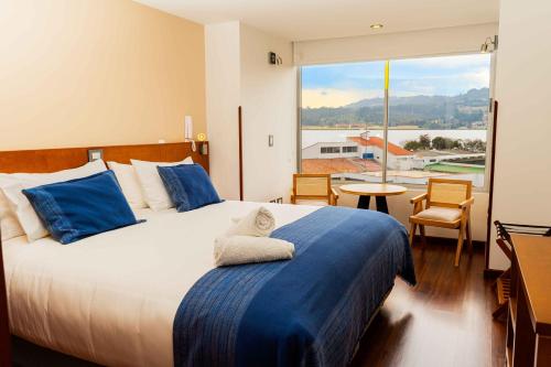 ein Schlafzimmer mit einem großen Bett und einem großen Fenster in der Unterkunft Samakwā Hotel Boutique in Paipa