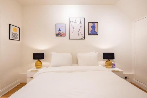 a bedroom with a large white bed with two lamps at Welcoming Flat with Sauna - Paddington in London