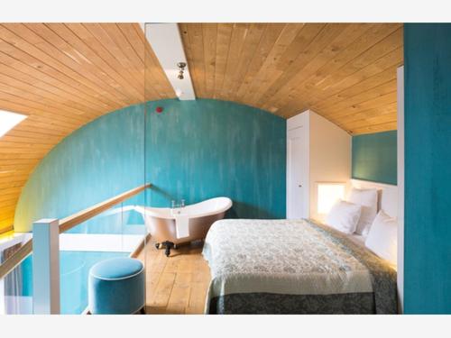 a bathroom with a bed and a tub and a sink at Suitehotel Posthoorn in Monnickendam