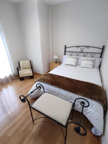 a bedroom with a large bed and a chair at Luz de la Avenida in Tomelloso