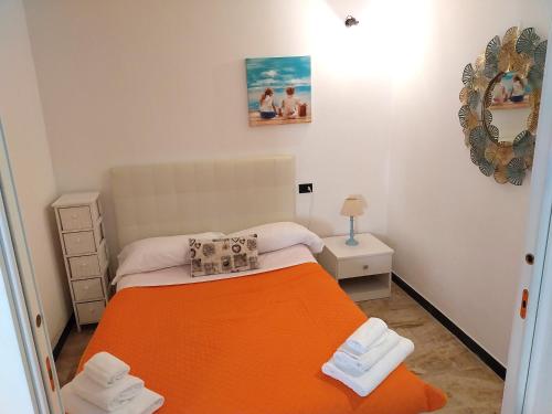 a small bedroom with a bed with an orange blanket at Fulvia's cozy apartment with terrace in Monterosso al Mare