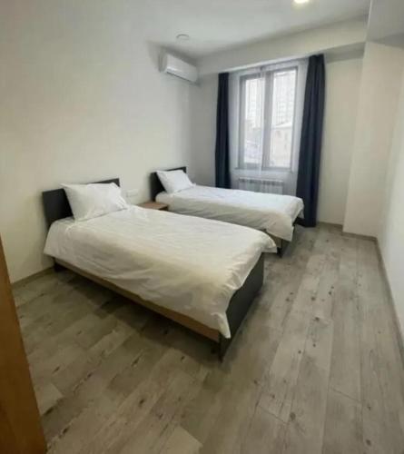 two beds in a room with a wooden floor at Lily house in Yerevan