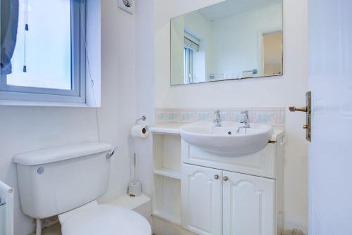La salle de bains blanche est pourvue de toilettes et d'un lavabo. dans l'établissement Comfortable 3 bed house in Chelmsford, à Chelmsford