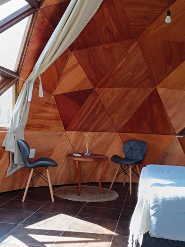 um quarto com uma parede de madeira com 2 cadeiras e uma mesa em Domo guidaí em Tacuarembó