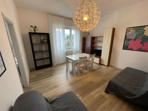 een woonkamer met een tafel en stoelen en een kroonluchter bij Casa Maggiana in Mandello del Lario