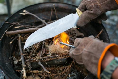 a person holding a large knife over a fire at Hakushu/Ojiro FLORA Campsite in the Natural Garden - Vacation STAY 11899v in Hokuto