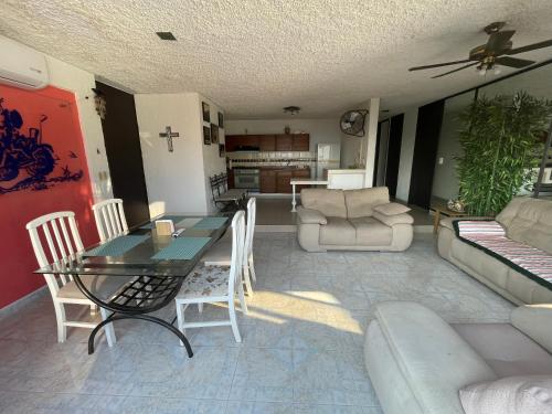 a living room with a table and chairs and a couch at Costera, depa hasta 9 personas con vista al mar, alberca, terraza y aire acondicionado in Acapulco