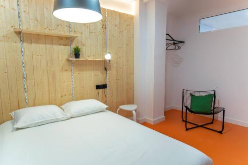 a bedroom with a white bed and a green chair at Koala Hostel Mercado in Alicante