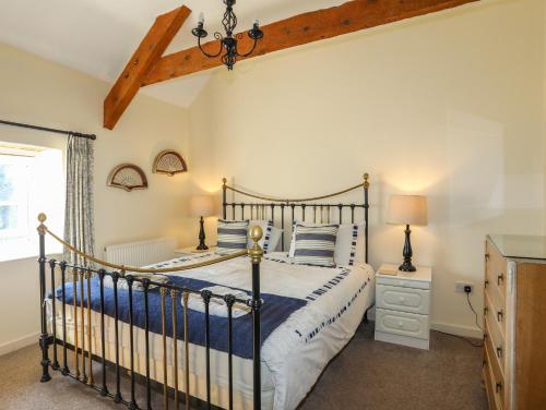 a bedroom with a black bed with blue and white pillows at Tan Twr - Chellow Cottage in Dwyran