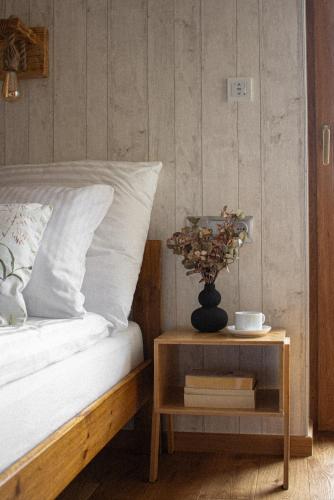 a bed with a table with a vase on it at Apartament Sarenka in Rogożnik