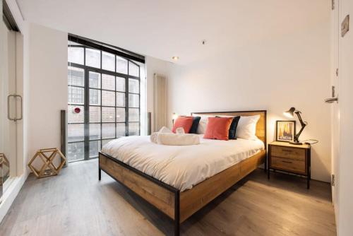 - une chambre avec un grand lit et une grande fenêtre dans l'établissement Central Soho Warehouse Loft with Concierge, à Londres