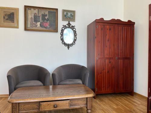 Habitación con 2 sillas, mesa de madera y armario. en APARTAMENT SPALSKIE KLIMATY, en Spała