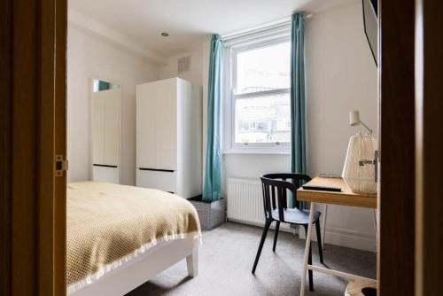 1 dormitorio con cama, escritorio y ventana en Modern 3-bed Duplex Apartment in Fitzrovia near Oxford Street, en Londres