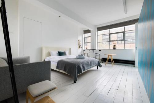 Spacious & Bright Loft Apartment - Shoreditch في لندن: غرفة نوم بيضاء مع سرير وطاولة