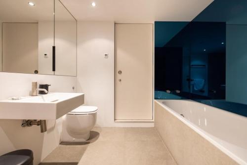 Spacious & Bright Loft Apartment - Shoreditch في لندن: حمام مع حوض ومرحاض وحوض استحمام