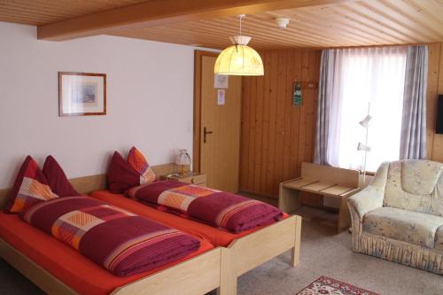 a bedroom with two beds and a chair at Hotel Blümlisalp in Grindelwald