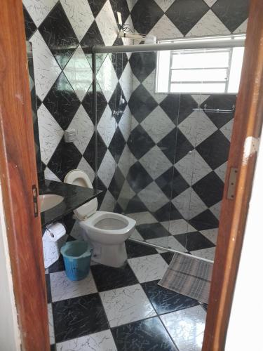 a bathroom with a toilet and a black and white tiled wall at Hotel Fazenda Recanto do Monte Alegre in Piraju