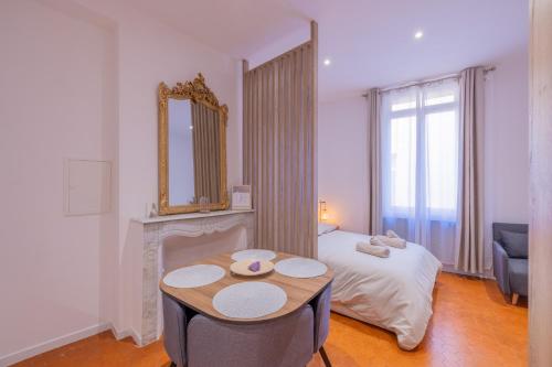 Cette chambre comprend un lit, une table et un miroir. dans l'établissement Appartement de Charme, à Aix-en-Provence