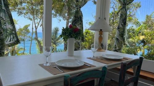 a table with two glasses and a table with a view of the ocean at BH58: Refúgio Romântico com Vista pro Mar in Ubatuba