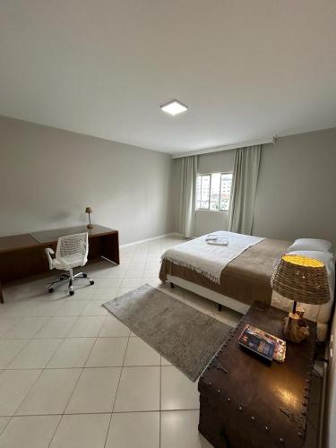 a bedroom with a bed and a desk and a chair at Apartamento NOVO no centro/Via Gastronômica in Lages