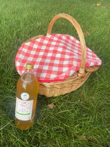 una cesta de picnic con una botella de sidra y un bolso en La Cabane dans les Arbres - Les Pieds dans le Pré, en Les Landes-Génusson