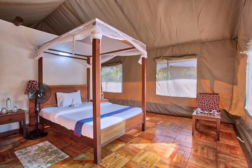 1 dormitorio con cama con dosel en una tienda de campaña en BoraBora Wildlife park and Luxury Tented Safari Camp Diani en Diani Beach