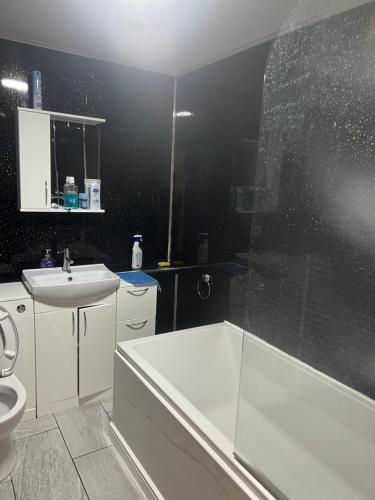 ein Badezimmer mit einer weißen Badewanne und einem Waschbecken in der Unterkunft Modern 3 bed house for 8 guest in Nevendon