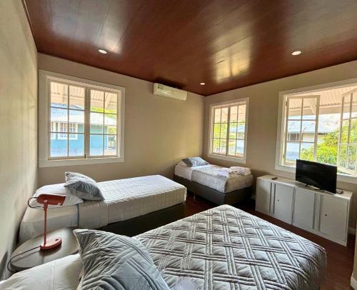 1 dormitorio con 2 camas, TV y ventanas en Casa Randa espaciosa y encantadora cerca a canal en Panamá