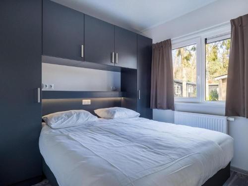 um quarto com uma cama grande e uma janela em Modern chalet with deck, in a natural area em Hoenderloo