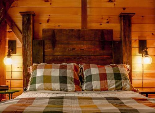 1 cama con 2 almohadas y pared de madera en Disarmingly Cozy 1BR Cabin, en Henderson
