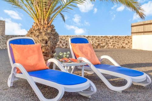 ラハレスにあるCasa Filale Sun and Relaxのヤシの木の横に座るビーチチェア2脚