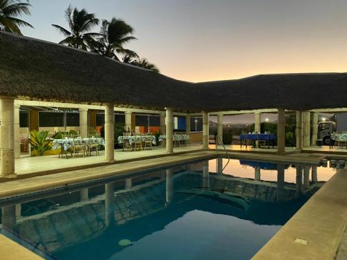 a resort swimming pool with a thatched roof at Hotel Yauco in Rosario