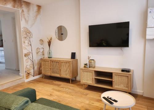 un salon avec une télévision à écran plat sur un mur dans l'établissement Cottage du Fort 50 mètres de la plage, à Le Portel