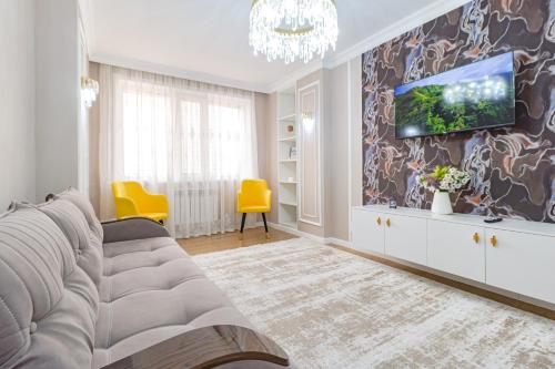 uma sala de estar com um sofá e uma televisão na parede em Amor de Astaná, ЖК Симфония, 3 комнатная em Astana
