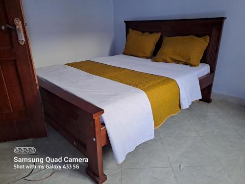 a bedroom with a bed with a wooden headboard at Kal Era Suites in Mbarara