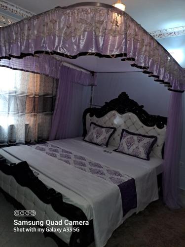 a bedroom with a canopy bed with purple curtains at Kal Era Suites in Mbarara