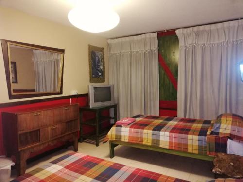 1 dormitorio con 2 camas y TV. en Flying Donkey en Otavalo