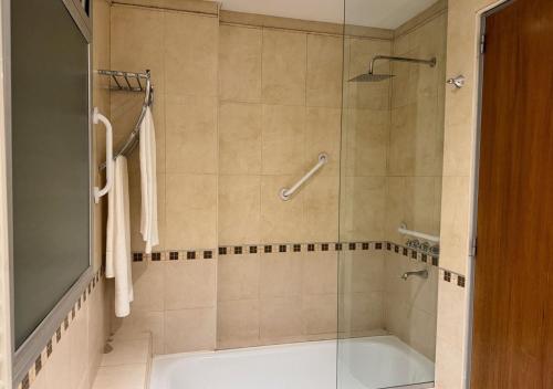 Roomie Salta by DOT Suites في سالتا: حمام مع دش وحوض استحمام