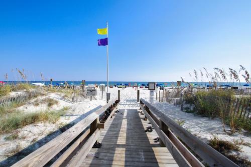 a boardwalk to the beach with two flags on it at Phoenix 10 Unit 1514 in Orange Beach