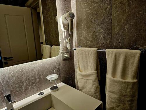 a bathroom with a sink and a mirror and towels at Blloku Suites, City Centre,Tirana in Tirana