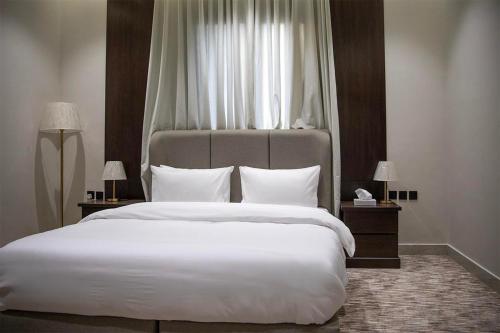 a bedroom with a large white bed with a window at فندق أرجان بارك ظهرة لبن Arjan Park Hotel in Riyadh