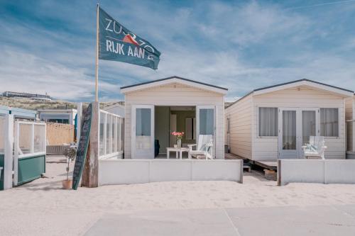 a beach house on the sand with a flag at Rijk aan Zee Ecolodges in Wijk aan Zee