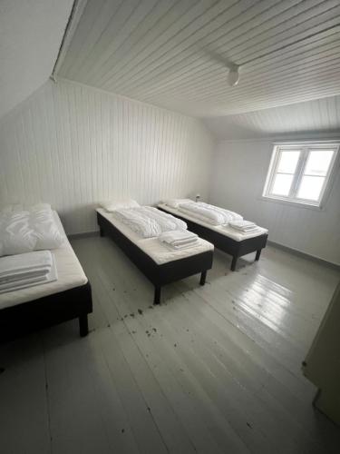 two beds in a small room with a window at Live Lofoten Fishermen's Cabins in Stamsund