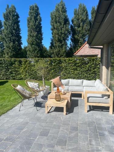 a patio with a couch and tables and chairs at Casa La Vista - Puur onthaasten met wijds polderzicht in Blankenberge