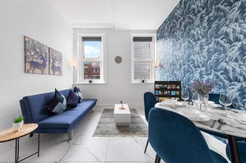 a dining room with a blue couch and a table at Modern 2 Bedroom Flat - Near Primrose Hill, Camden Market, Regent's Park - Good Links to Kings Cross, Euston, Finchley Road Station - NW3 London in London