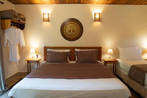 two beds in a room with two lamps on the wall at Pousada Lua Clara in Alto Paraíso de Goiás