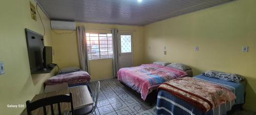 1 dormitorio con 2 camas y TV. en Loft Confortável no Centro en Chapecó